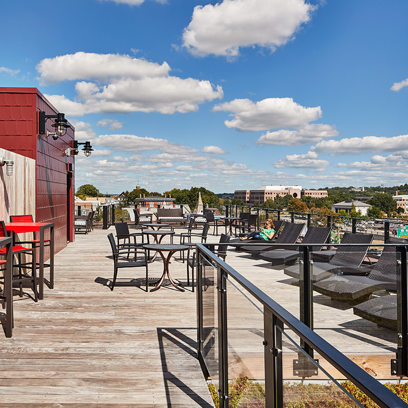 Rooftop deck with black lounge seating and a view of a city
