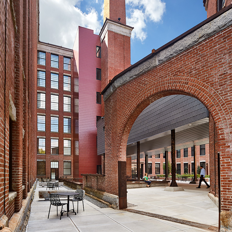 Outdoor courtyard with a large brick arch and metal patio seating