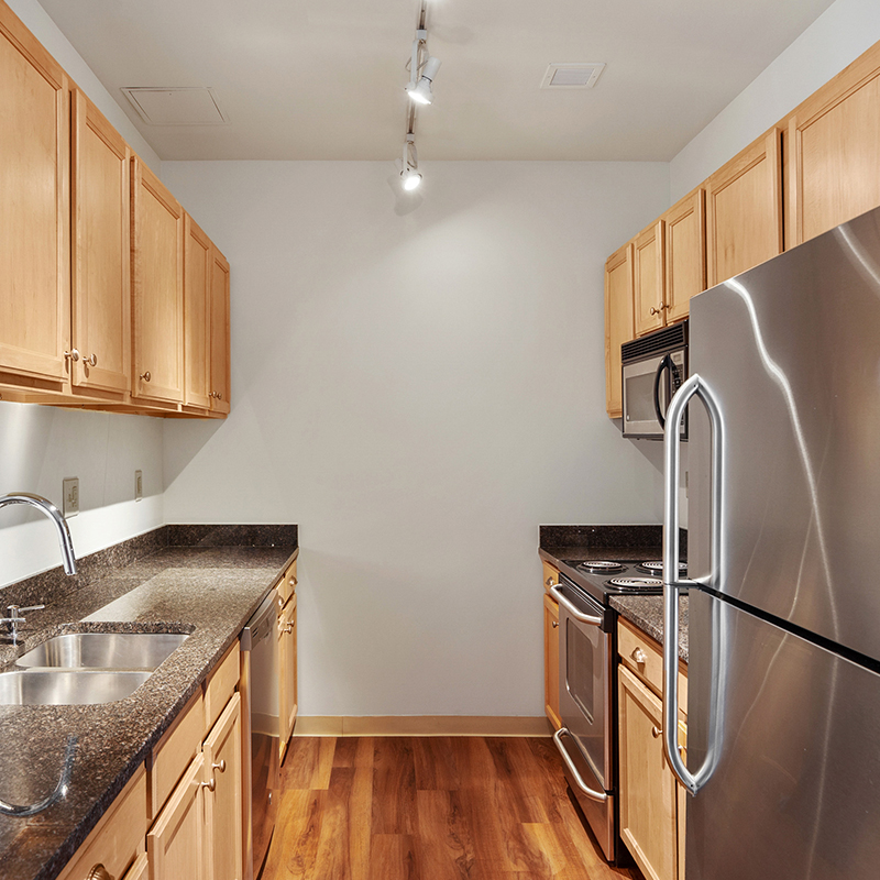 Stylish apartment kitchen with new appliances and wood cabinetry